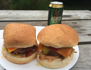 Zwei Burger und eine Dose Bier auf einem Picknicktisch